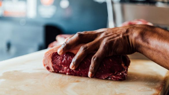 Raw beef being held on a chopping board