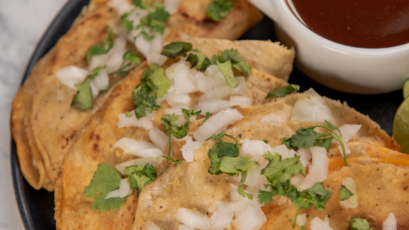 close up of three beef birria tacos garnished with white onion and corriander