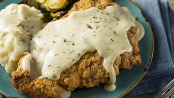 country fried steak with white gravy on a green plate